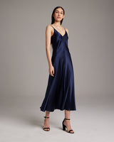 Model wearing a navy V-neck slip dress with spaghetti straps