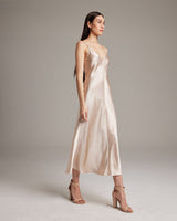 Model wearing a beige V-neck slip dress with spaghetti straps