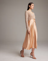 Model wearing a painted loose knit cropped sweater in sand color, showcasing its relaxed fit and asymmetrical hemline.