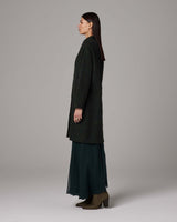 Model wearing a handwoven alpaca Lineas coat in forest color, side view