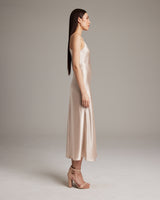 Model wearing a beige V-neck slip dress with spaghetti straps