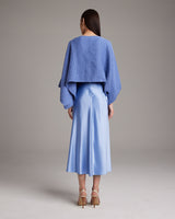 Back view of a blue textured cotton bolero worn over a light blue dress