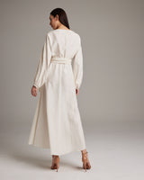 Back view of a model wearing a long ivory peasant dress with a sash