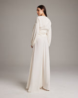 Model wearing a white peasant blouse with puff sleeves and a flowing skirt from the back