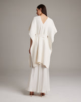 Back view of a woman wearing a textured cotton solid kaftan over a white slipdress