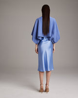 Model wearing a blue textured cotton crop top over a satin blue skirt from the back