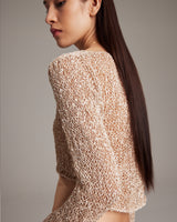 Model wearing a painted loose knit cropped sweater, showing the back view.