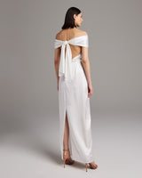 Back view of a model wearing a bridal convertible halter dress with a tied sash and slit.
