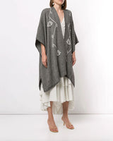 Model wearing a grey Copihue Duster in Baby Alpaca over a white dress, standing on a plain background.