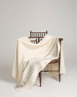Wide Diagonal Alpaca Blanket draped over a chair, featuring a geometric pattern.
