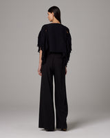 Back view of a model wearing a black Lace Fringe Crop Top with fringe details