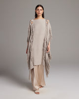 Model wearing a beige Lace Fringe Manta with fringe details over a light outfit.