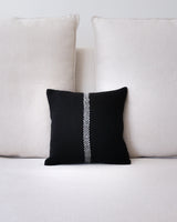 Black and ivory square pillow with a central line design, placed on a sofa