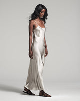 Model wearing a liquid silk slipdress in silver, standing sideways
