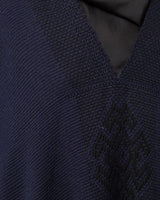 Close-up of navy poncho with Araña symbol woven in.