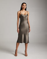 Model wearing a sage green VOZ midi slip dress made of silk charmeuse