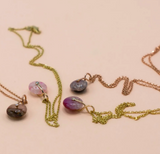 Two necklaces featuring rose quartz and gold chains on a light background.