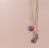 Three necklaces featuring rose quartz and diamond bezels on a soft background