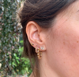 Close-up of a person wearing Millapani Curva Grande Earrings, showcasing their design and style.