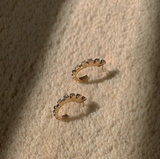 Curved gold earrings with diamonds, inspired by Mapuche symbol