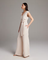 Model wearing a pearl V Neck Jumpsuit with a belt, side view