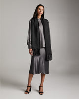 Model wearing the Lineas Fringe Scarf in black, styled with a grey dress.