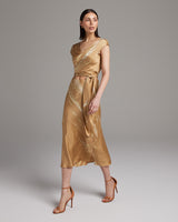 Model wearing a gold tie dye bias midi skirt with a wrap bralette and heels