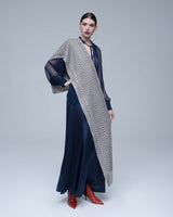 Model wearing a chevron scarf in ivory and black, styled with a navy dress and red boots.