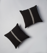 Two black pillows with a white stripe design on a gray background