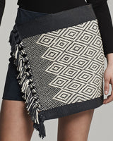 Detail of Mini Wrap Skirt featuring black and ivory diamond pattern with fringe