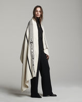 Model wearing a Wide Diagonal Alpaca Wrap in ivory and grey, showcasing its design and texture.