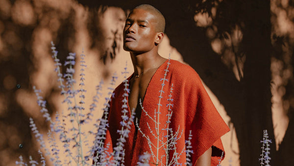 Darnell Thomas wearing a red garment standing among purple flowers