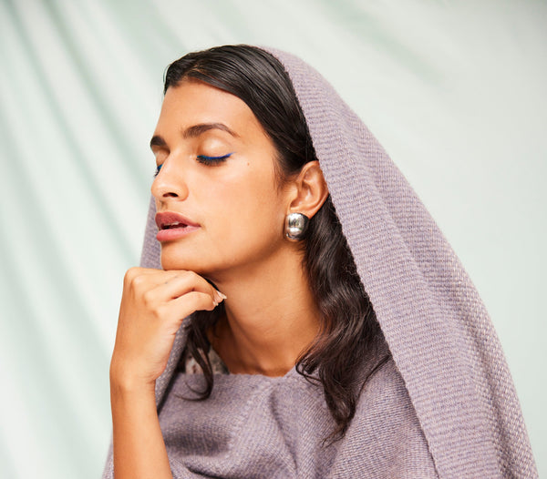 Cassandra Mayela with a thoughtful expression, wearing a purple shawl and earrings