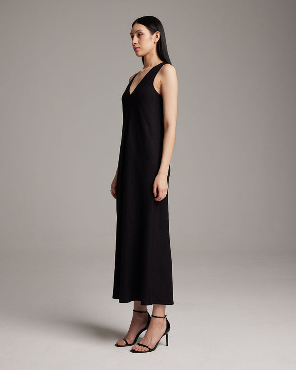 Model wearing a black linen V neck maxi dress, side view