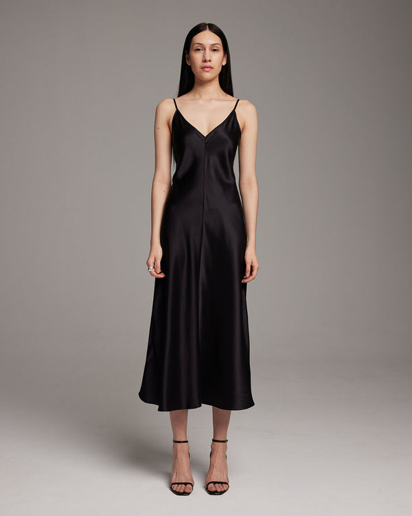 Model wearing a black V-neck slip dress with spaghetti straps