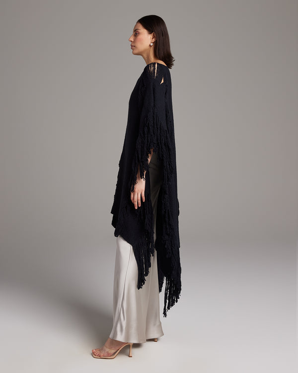 Model wearing a black Lace Fringe Manta over a silk outfit, showcasing its flowy design.
