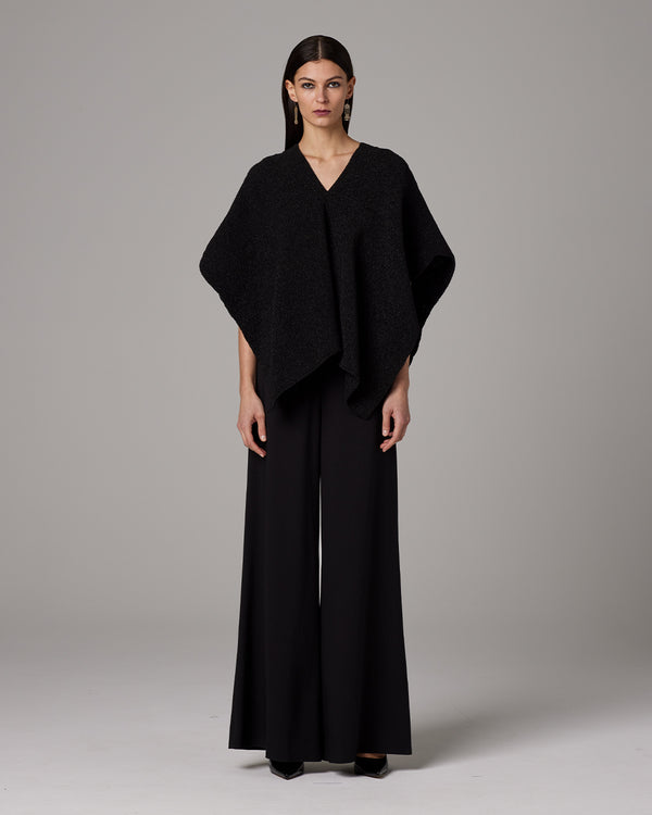 Model wearing a black Manta Captiva poncho with wide pants