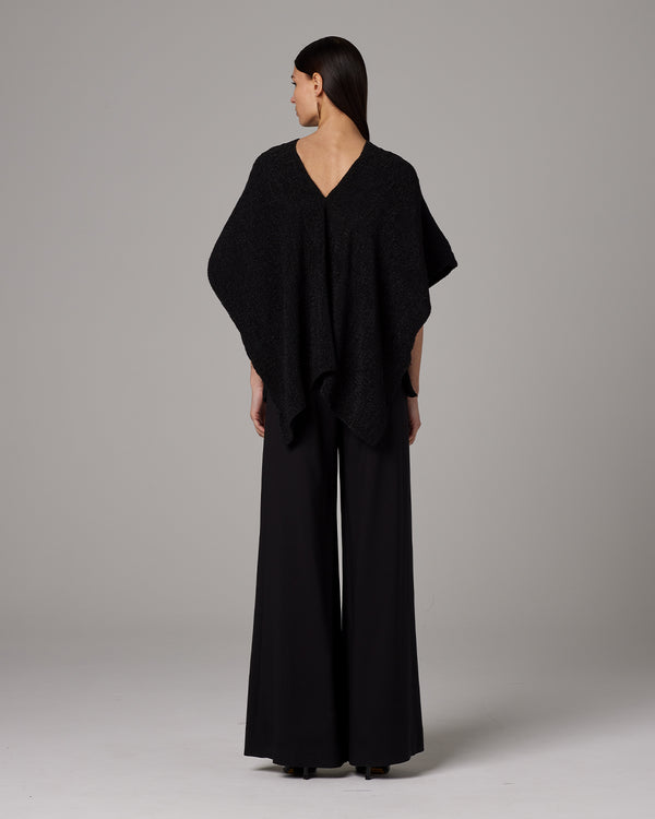 Back view of a woman wearing a black Manta Captiva poncho